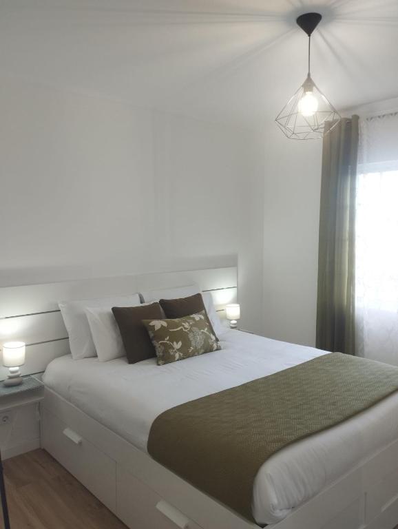 a white bedroom with a large white bed with pillows at Green Passion in Ponta Delgada