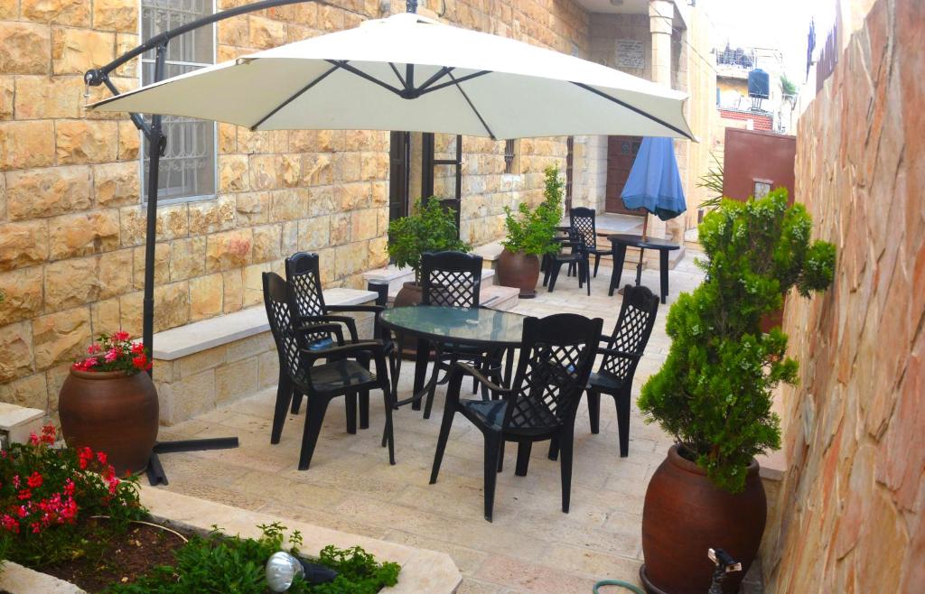 une terrasse avec une table, des chaises et un parasol dans l'établissement St Thomas Home's Guesthouse - Jerusalem, à Jérusalem