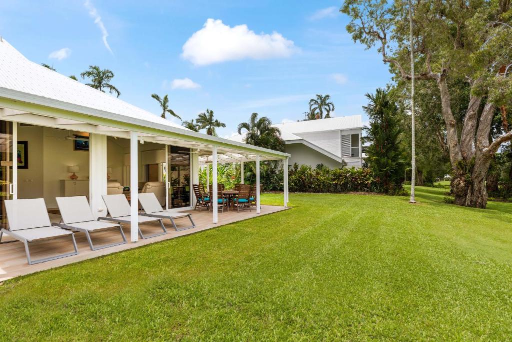 un patio con sillas blancas y un patio en Mirage Resort Villa 134 with access to Sheraton Facilities, en Port Douglas