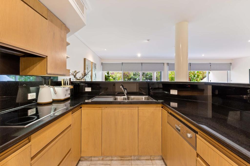 a kitchen with wooden cabinets and a sink at Mirage Resort Villa 157 with access to Sheraton Facilities in Port Douglas