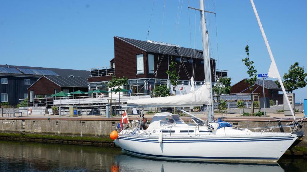 een witte zeilboot aangemeerd in een haven met een huis bij Lunds Hotel in Bogense