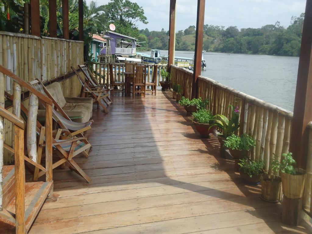 a wooden porch with chairs and plants on the water at Hotel Lara's Planet in El Castillo de La Concepción