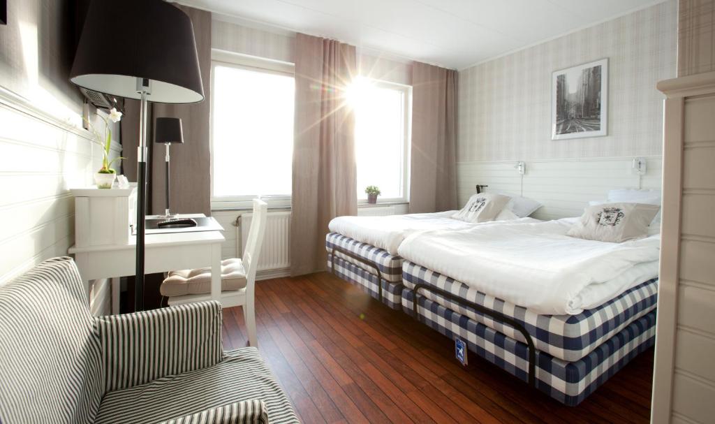 een hotelkamer met 2 bedden, een bureau en een stoel bij Lages Motel in Borås