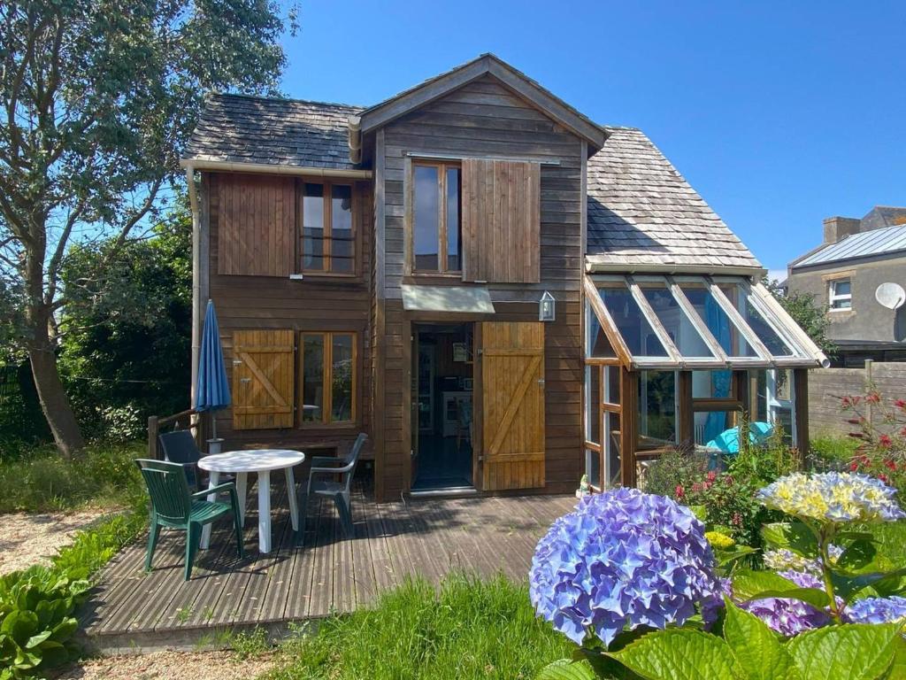 a tiny house with a table and chairs on a deck at Maison avec jardin clos et WIFI à Trégastel - FR-1-368-465 in Trégastel