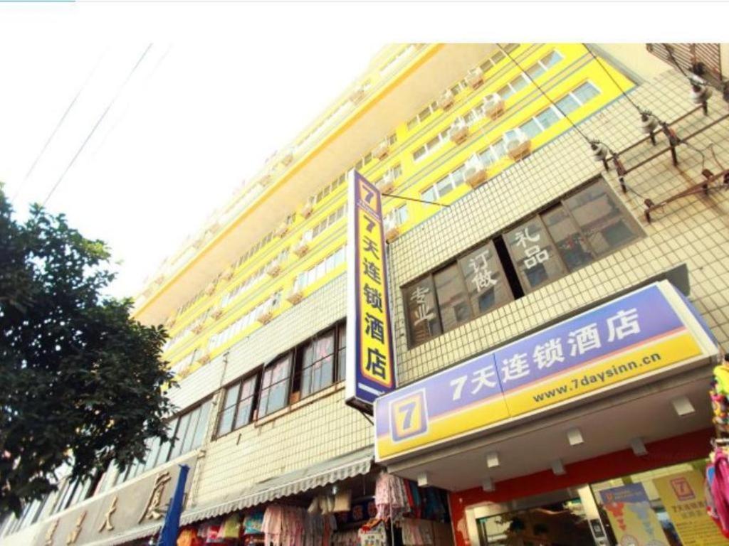 成都7 Days Inn Chengdu North Railway Metro Station的一座黄色的建筑，前面有一块招牌