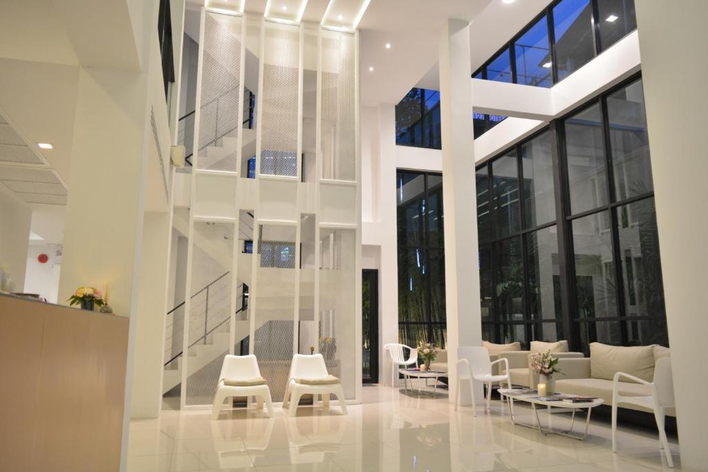 a lobby with white furniture and large windows at Rezt Bangkok in Bangkok