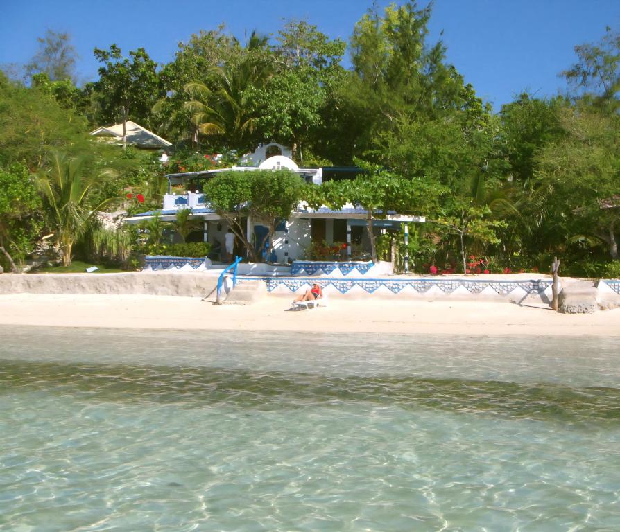 a beach with a house and the water at Casa de la Playa Beach Resort in Siquijor