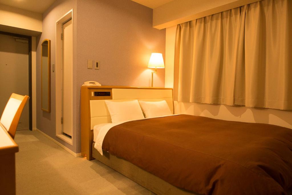 Postel nebo postele na pokoji v ubytování Nisshin Namba Inn