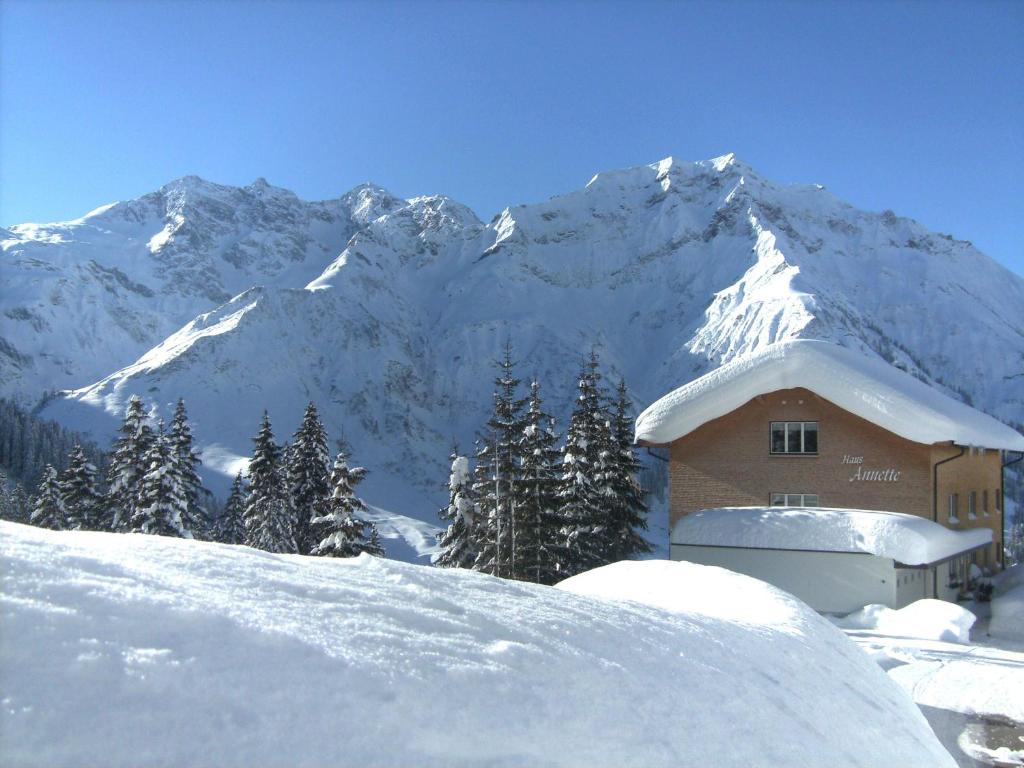un edificio con montañas cubiertas de nieve en el fondo en Haus Annette, en Schröcken