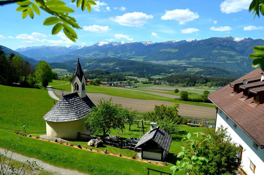 una iglesia en una colina con montañas en el fondo en Weliserhof en Brunico