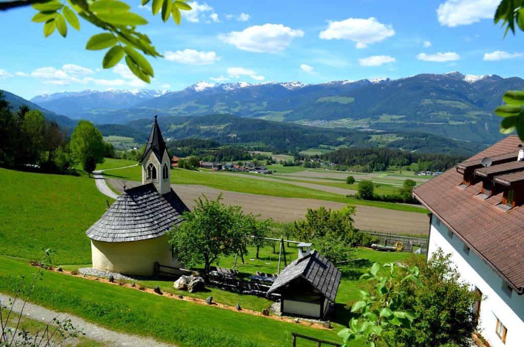 een kerk op een heuvel met bergen op de achtergrond bij Weliserhof in Brunico