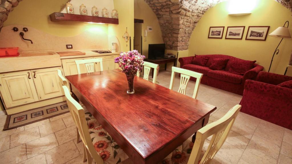 a kitchen and living room with a wooden table with flowers on it at Residenze da sogno in Bosa
