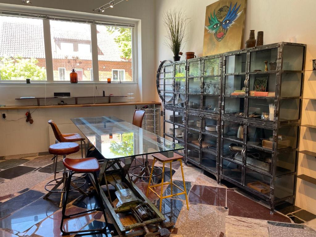 a dining room with a glass table and a shelf of dishes at Udda boende med wow-känsla och spabad på terrassen in Löderup