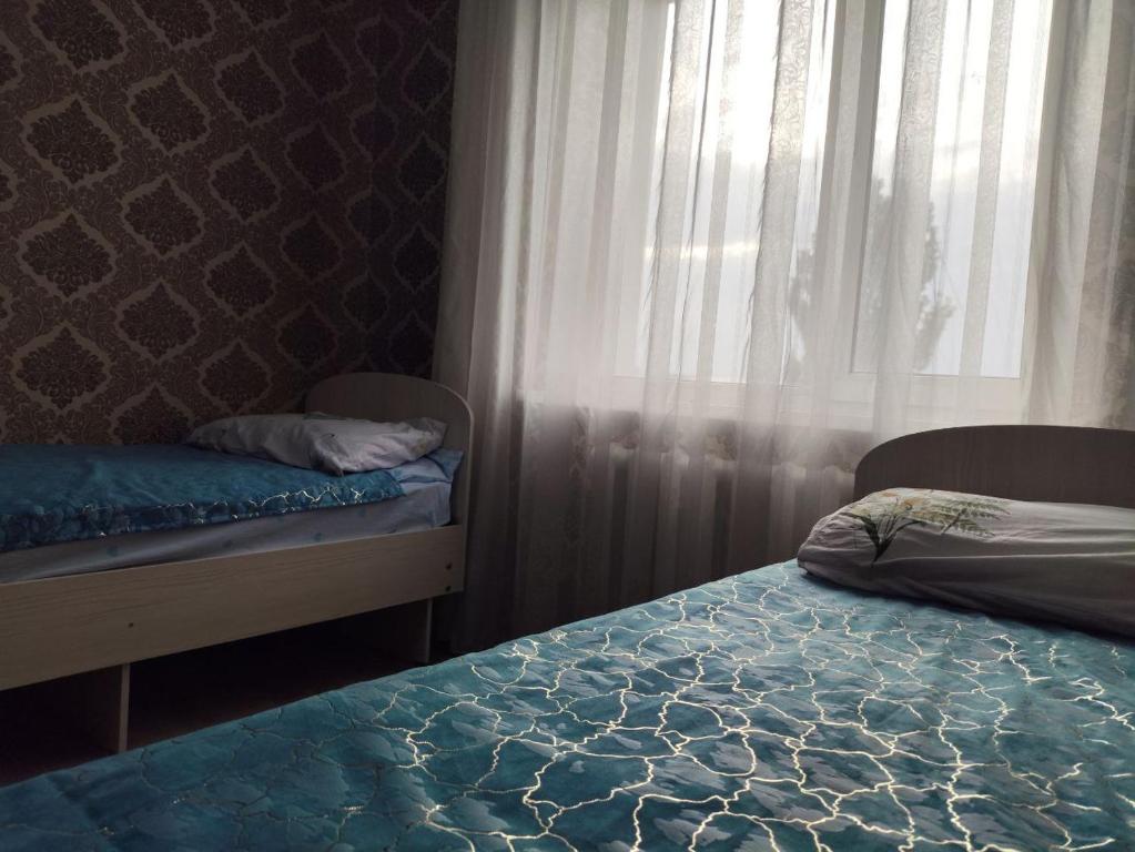 a bedroom with two beds and a window with curtains at RoomZoom in Karakol