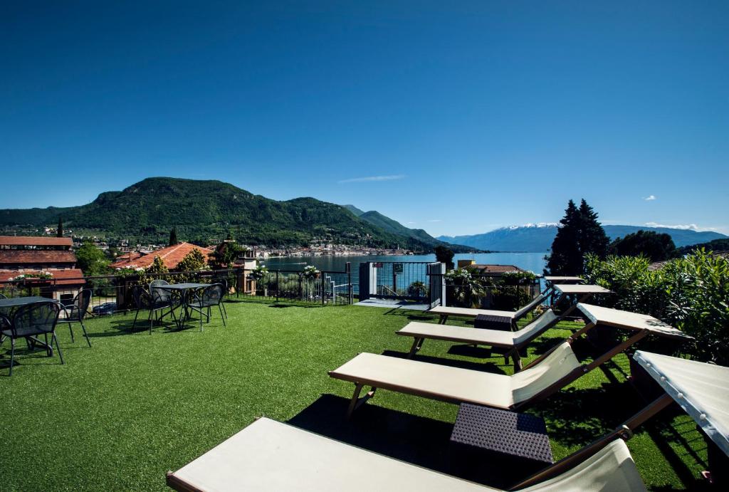 una fila di tavoli e sedie su un prato con un lago di Hotel Conca d'Oro a Salò