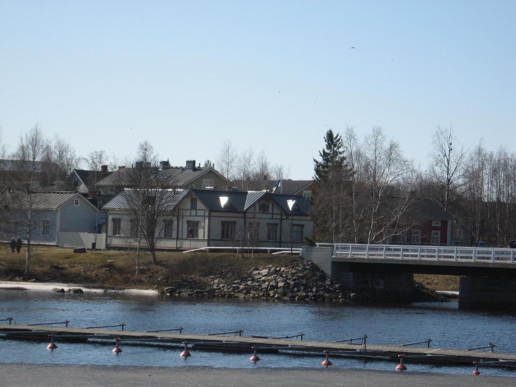 a bridge over a river with a house in the background at Pikisaari Apartment in Oulu