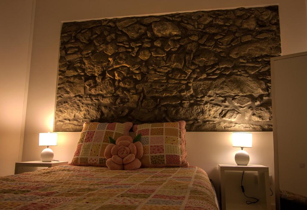 a bedroom with a large stone wall above a bed at Casa do Simão in Nordeste