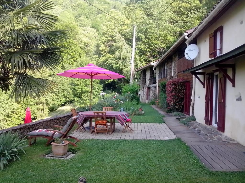 une terrasse avec une table et un parasol rose dans l'établissement Gîte de la Ouedolle, à Sengouagnet