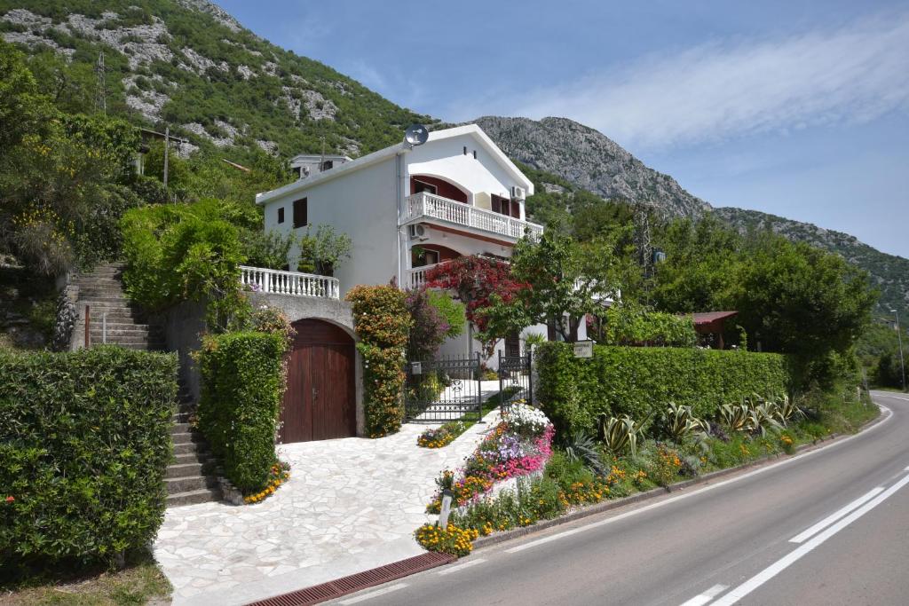 una casa sul fianco di una collina con dei fiori di Apartments Biga a Donji Morinj