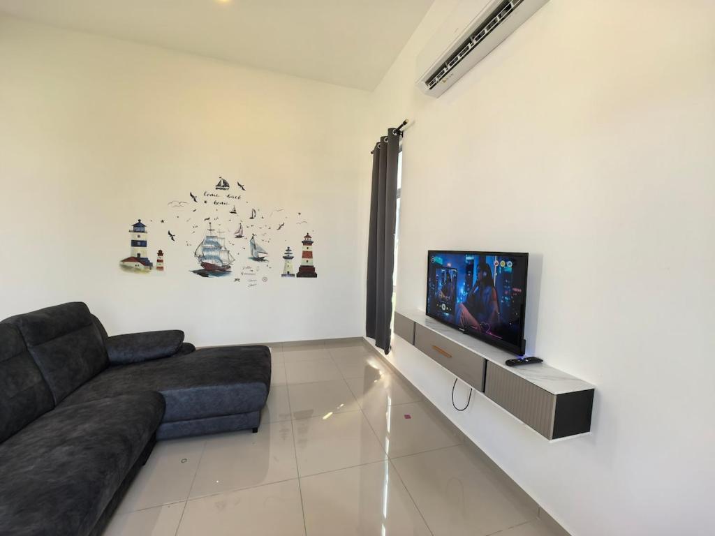 a living room with a couch and a flat screen tv at Padang Serai Wangi Homestay 91 in Padang Serai