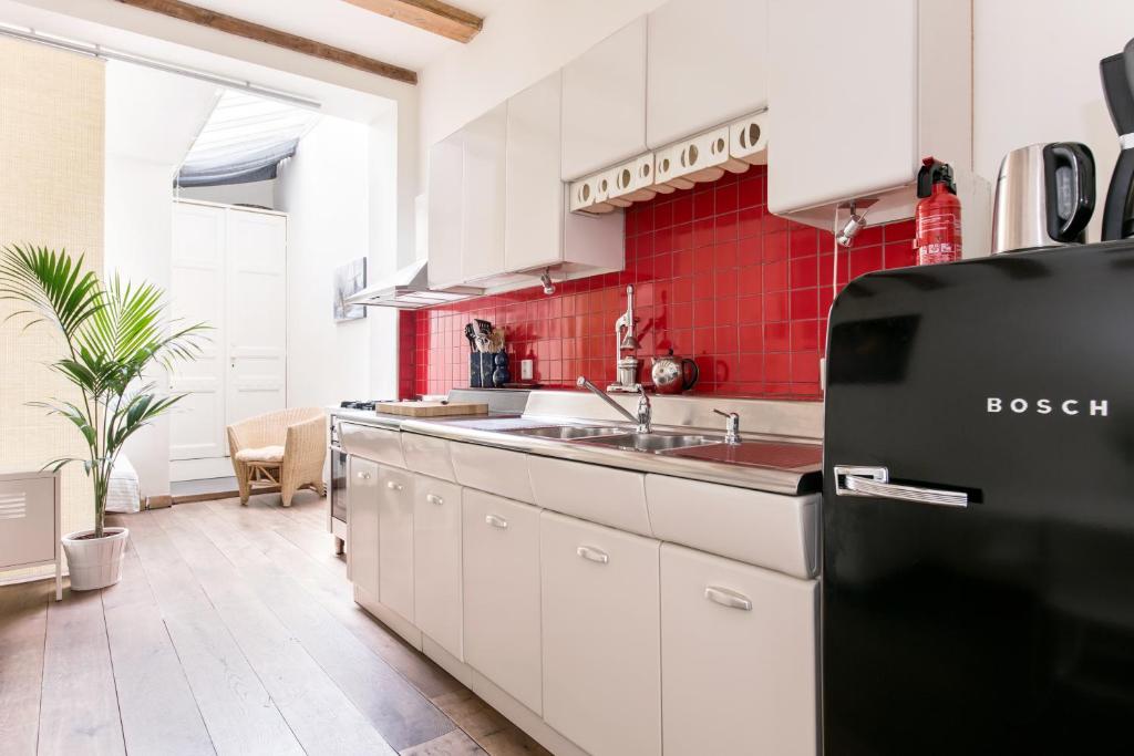 a kitchen with white cabinets and a black refrigerator at GH Amsterdam in Amsterdam
