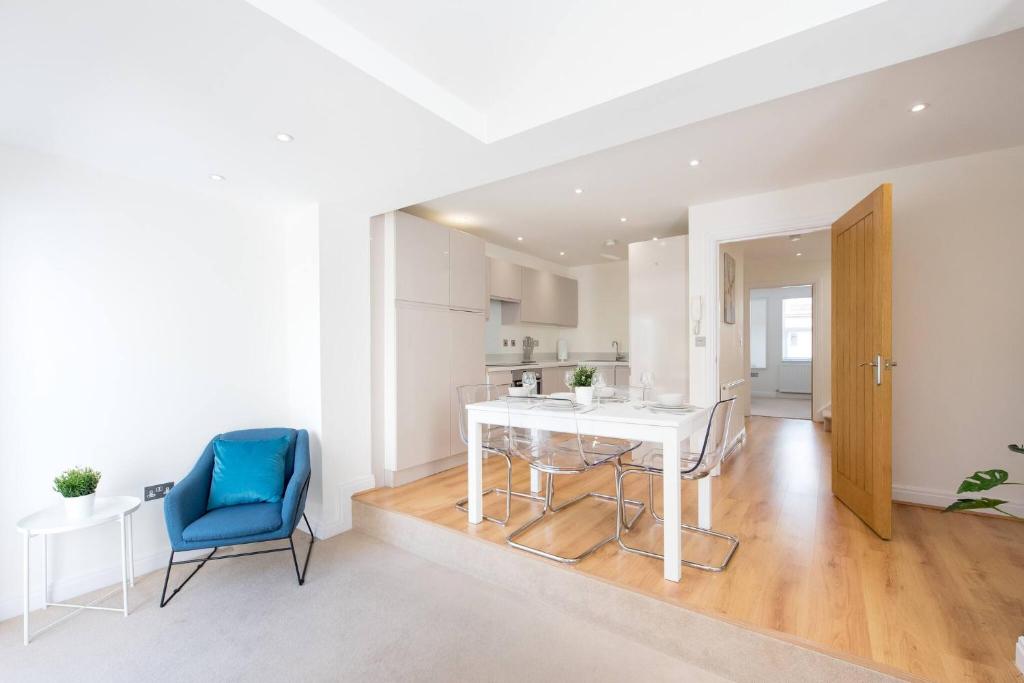 a white kitchen with a table and a blue chair at Romford - Balcony - Outdoor Space - Parking Space in Romford