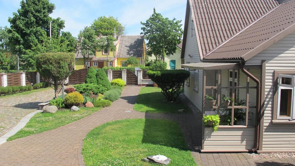 a backyard with a brick walkway next to a house at Smilčių namelis in Palanga