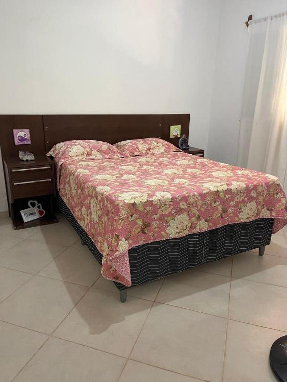 a bedroom with a bed with a flowered blanket on it at Conexão oito in Alto Paraíso de Goiás