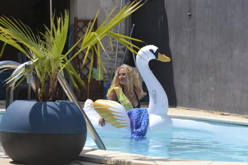 a woman sitting next to a swan in a pool at Grande chambre familliale pour 4 à 5 personnes in Chef-Boutonne