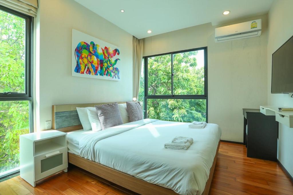 Un dormitorio con una gran cama blanca y dos ventanas. en C130 Steps to Beach 1BR Condo Gym, Pool & Sauna, en Rawai Beach