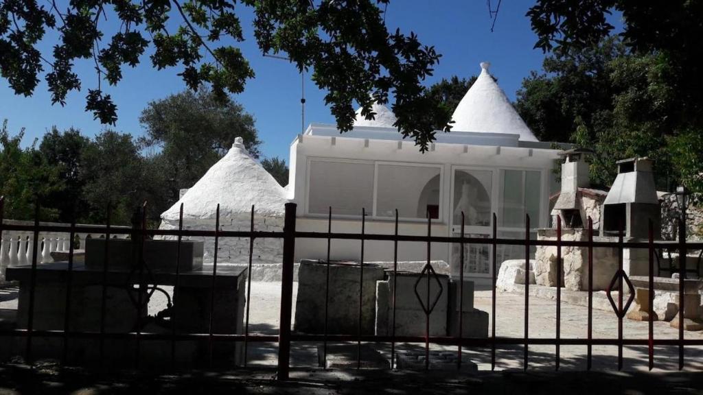 a white building with a fence in front of it at i trulli di Holly in Selva di Fasano