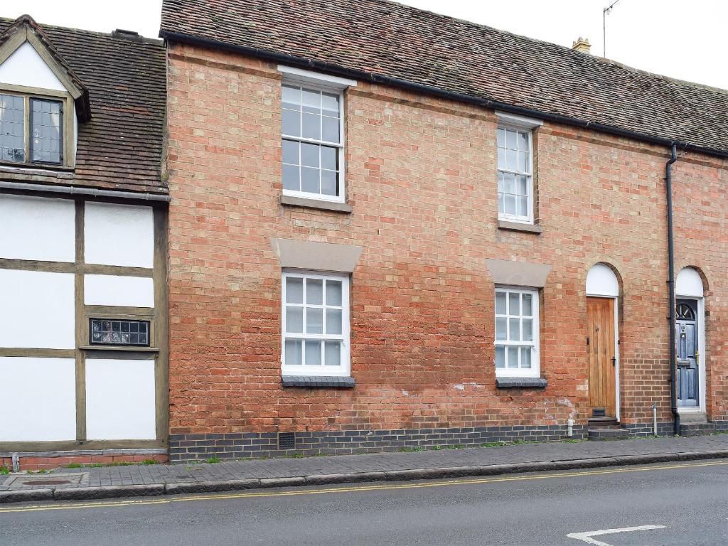 a brick building with white windows on a street at The Lovely Old Cottage in Stratford-upon-Avon