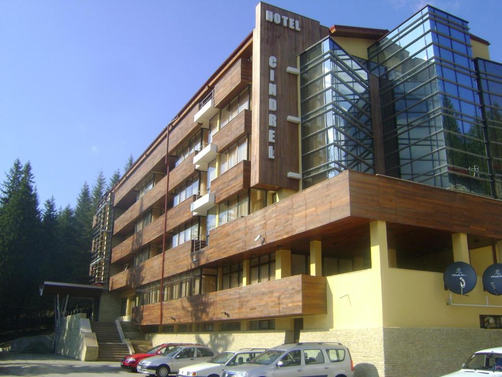 un edificio con dos coches estacionados frente a él en Hotel Cindrel, en Păltiniş
