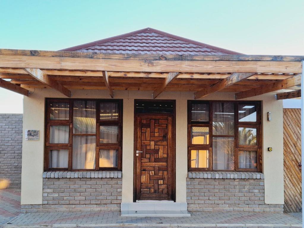 a house with a wooden roof and two doors at Duineveld Self Catering Cottage in Kalkrand