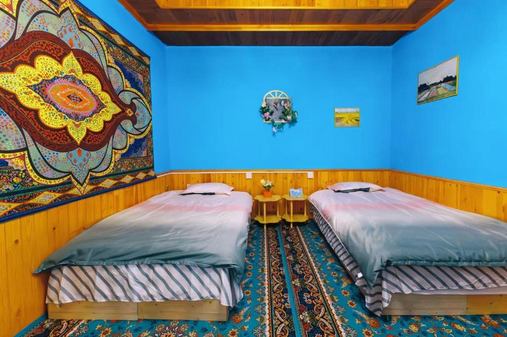 伊宁Good Morning International Chain Hostel Of Yining City的房间里有两张床，墙上挂着一幅画