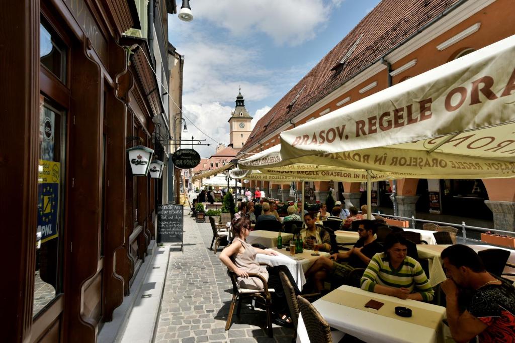 un grupo de personas sentadas en las mesas fuera de un restaurante en Da Vinci, en Brasov
