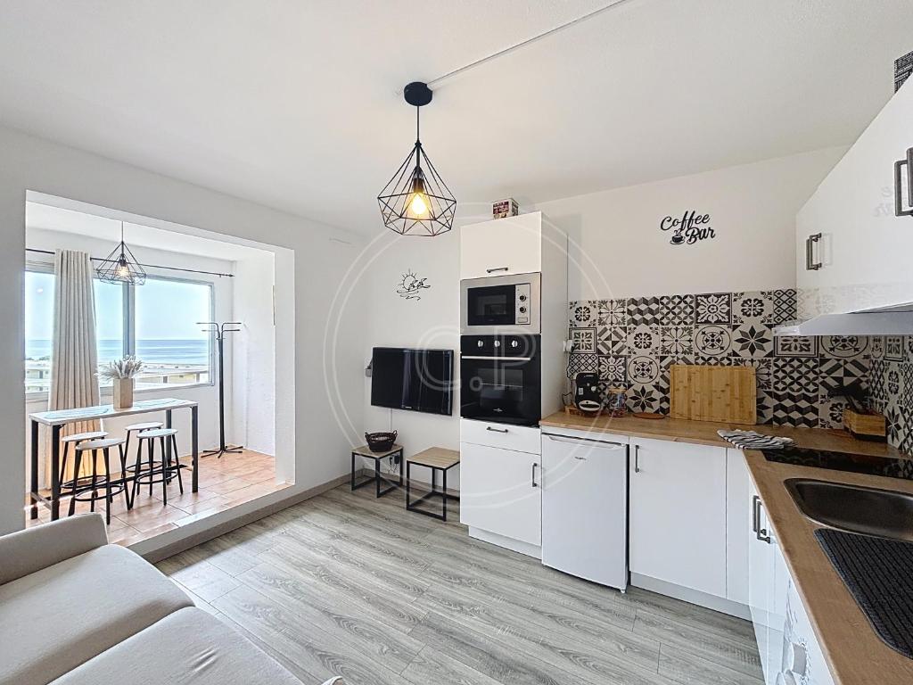 une cuisine avec des armoires blanches et une table avec des chaises dans l'établissement Bay View Studio climatisé 4 pers vue mer by LaConciergerie13, à La Ciotat