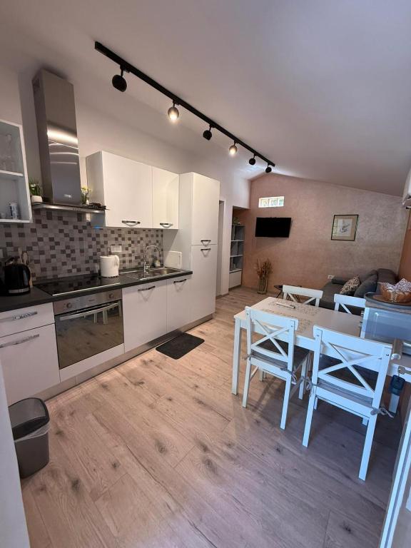 Una cocina con gabinetes blancos y una mesa y sillas. en Apartman Etta - Šišan, en Šišan