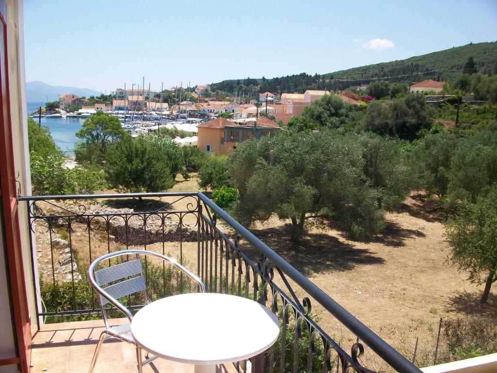 a white table and chair on a balcony with a view at Rosa's Studios in Fiskardo