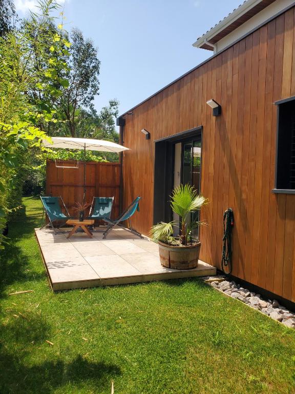 un patio avec deux chaises et une table à côté d'un bâtiment dans l'établissement Au calme du Golf - Appartement Chic 5 étoiles, à Hossegor
