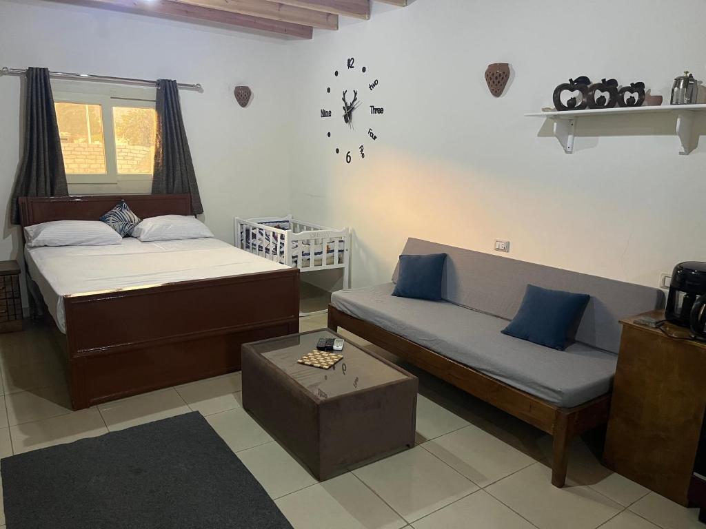 ein Schlafzimmer mit zwei Betten und einer Couch und einer Uhr an der Wand in der Unterkunft Dahab Smart Suite AC, Air fryer, & Bike in Dahab