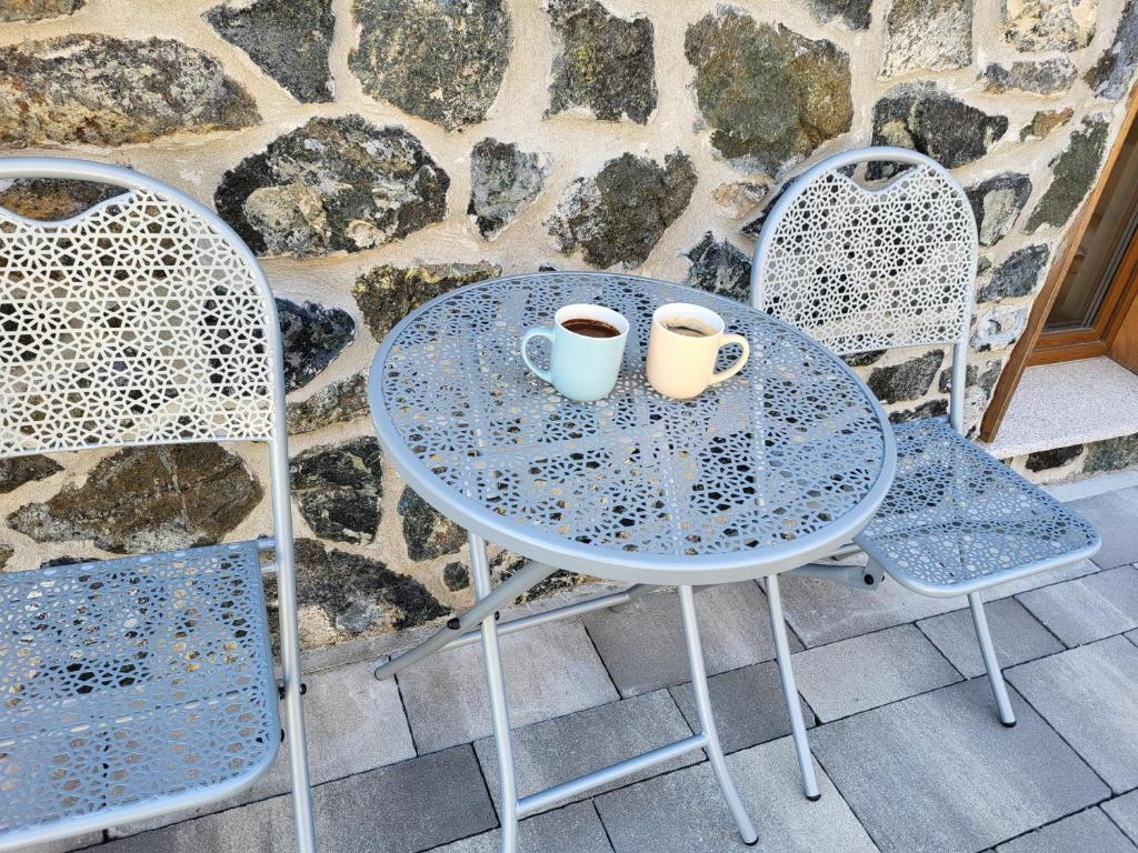 two cups on a table with two chairs at Alpino in Divčibare
