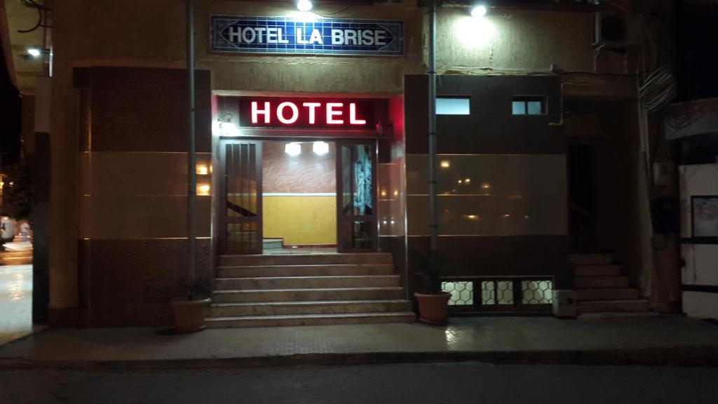 a hotel at night with a neon sign on the door at Hotel la brise in Aïn El Turk