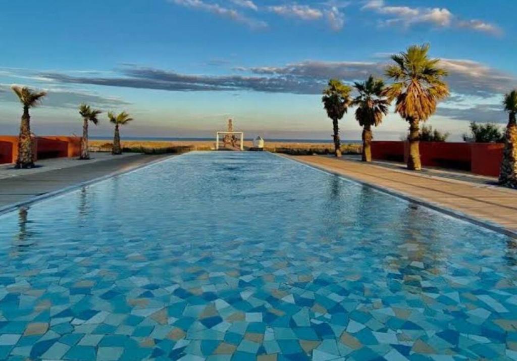 una grande piscina con palme e un monumento di Maison de plage avec grande terrasse privée a Leucate Plage