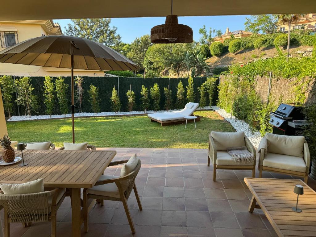a patio with a table and chairs and an umbrella at Casa Estelle - cozy with lovely garden - Mijas - Riviera del Sol in Mijas Costa