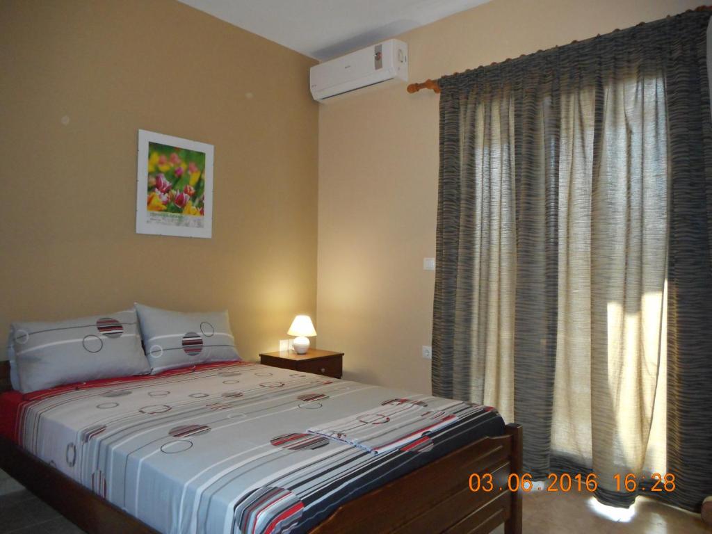 a bedroom with a large bed and a window at Dimitra's Apartments in Olympiaki Akti