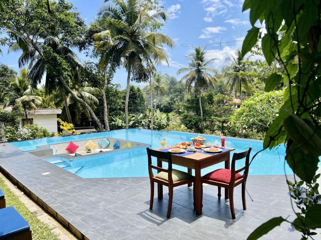a table and chairs in front of a swimming pool at Muthu Nila villas- Mirissa in Mirissa
