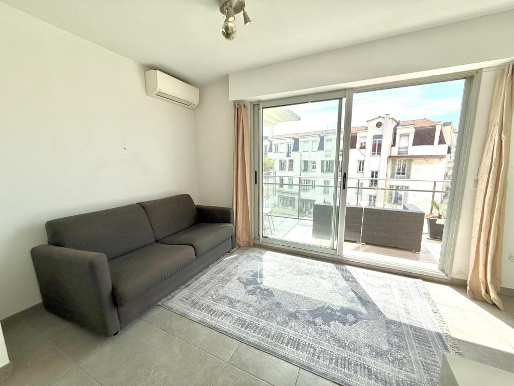 un salon avec un canapé et une grande fenêtre dans l'établissement Studio Terrasse 3ème étage, climatisation coeur de Nice, à Nice