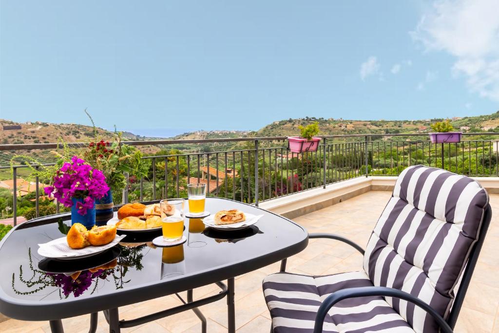 a table with food and drinks on a balcony at Granatelli Holiday Home in Altavilla Milicia