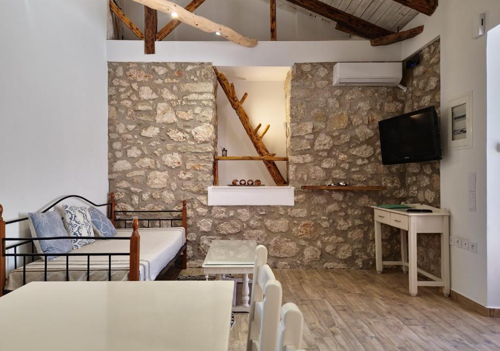 a living room with a couch and a tv on a wall at Alekos Cozy Stone 2BR Home Karya Center in Lefkada Town